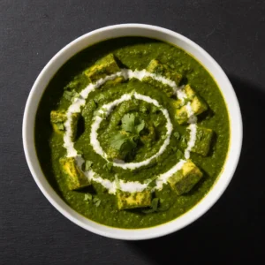 rustic-punjabi-saag-paneer-with-white-butter-on-top-served-with-makki-di-roti-on-a-dark-wooden-surface